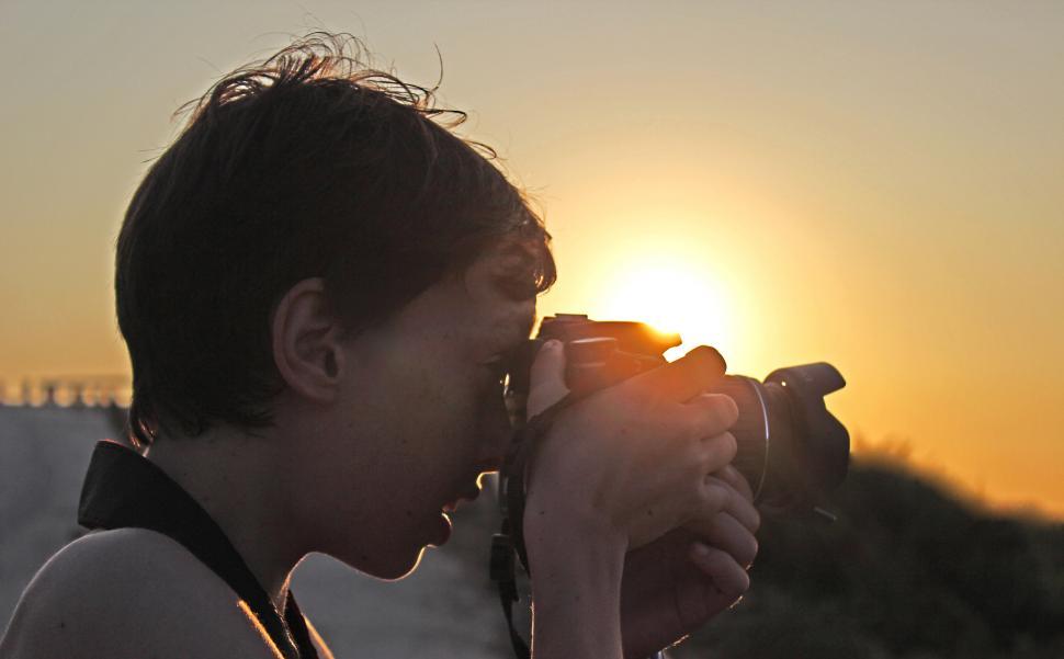 Free Image of Child taking a picture with DSLR camera at sunset 