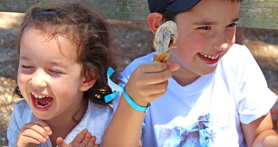 Free Image of Children eating chicken with their hands and smiling 