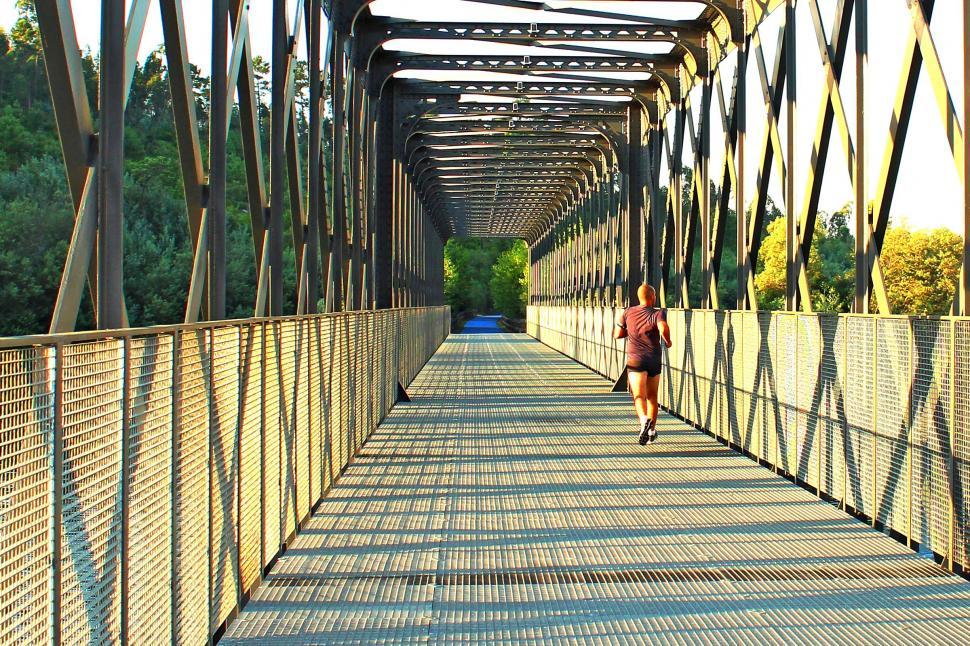Free Image of Runner crossing a metal bridge at sunrise during morning trainin 