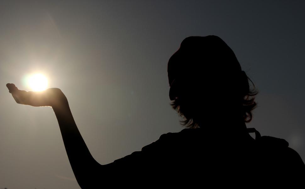 Free Image of Silhouette of a child holding the sun in his right hand 