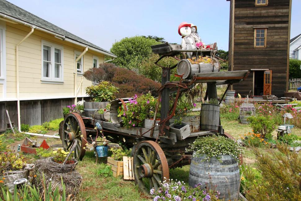 Free Image of Old Wooden Wagon Filled With Plants in Front of House 