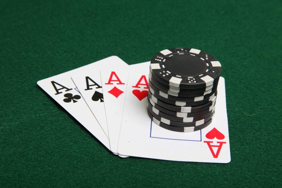 Free Image of Four aces with black poker chips stacked on top. 