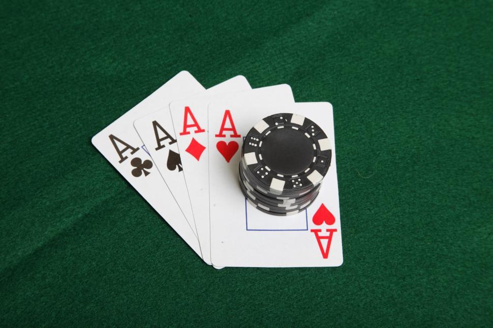Free Image of Four aces with black poker chips stacked on top. 