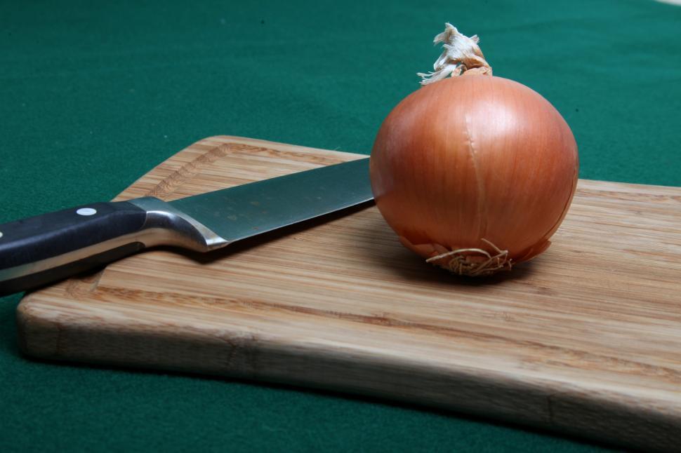Free Image of Onion and knife on wooden cutting board 