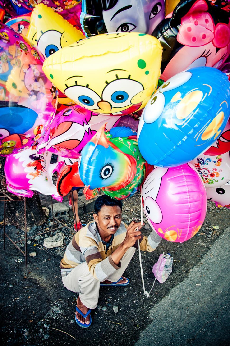Free Image of Asian man selling balloons in the street 
