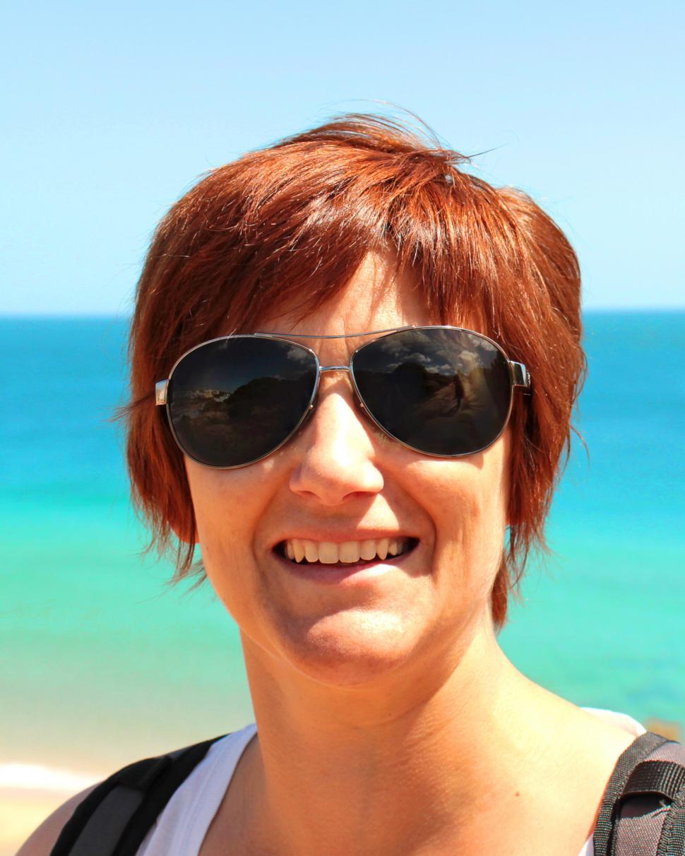 Free Image of Woman With Red Hair and Sunglasses on a Beach 