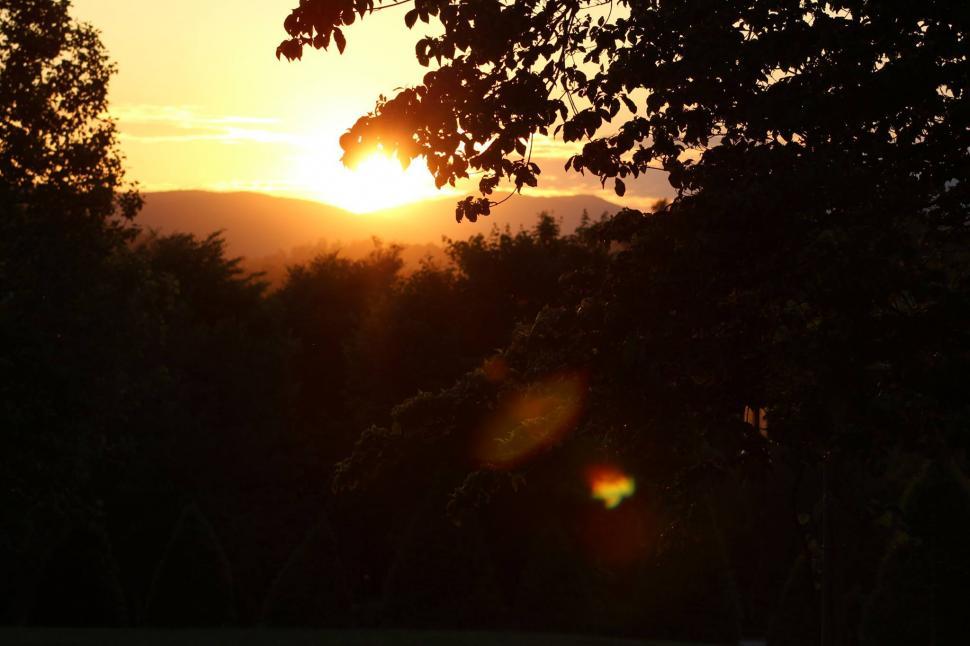 Free Image of Sun Setting Over Trees and Mountains 