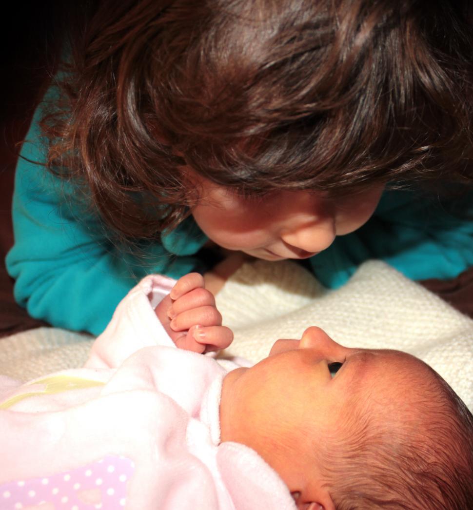 Free Image of Toddler looking her younger baby sister in the eyes 