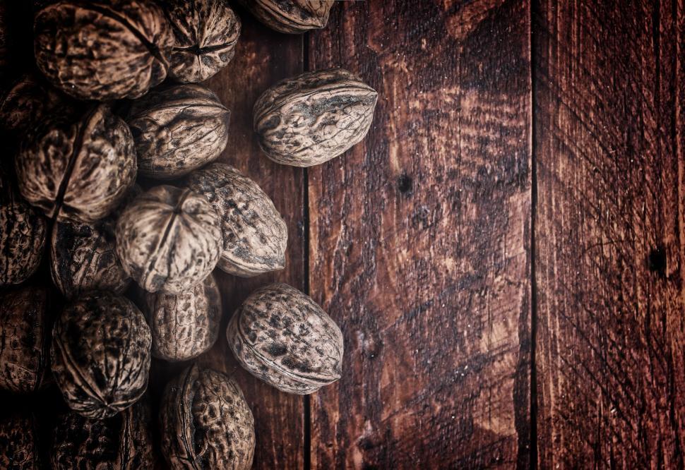Free Image of Whole walnuts on rustic old wooden table 