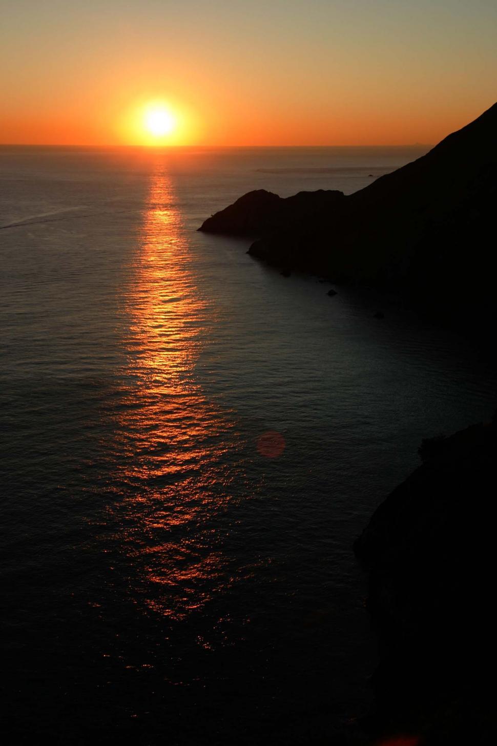 Free Image of sun sunset ocean water red circle hot glow glowing coast shore shoreline coastal beach 