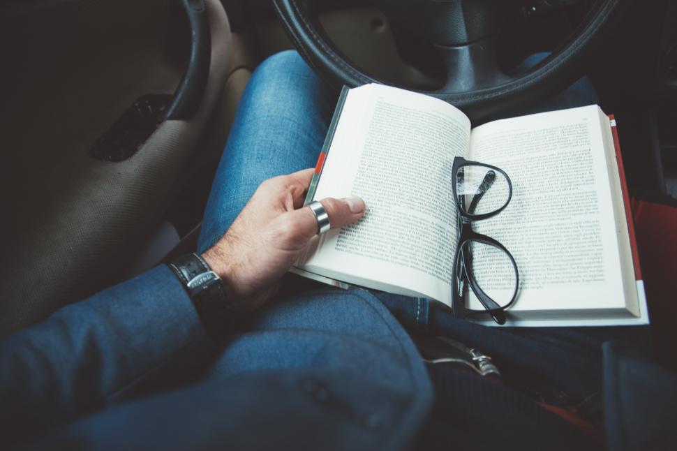 Free Image of Open book in the lap of a driver at a car 