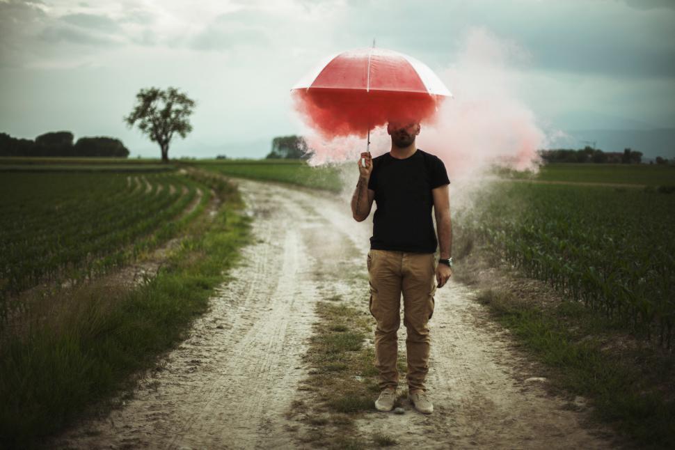 Free Image of Man Walking Down a Dirt Road Holding an Umbrella 