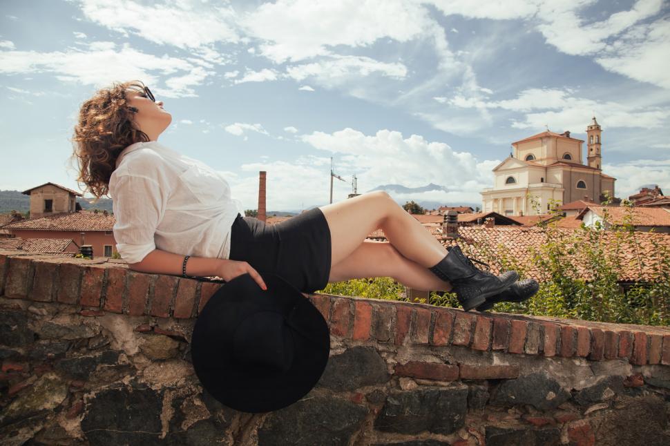 Free Image of Woman Sitting on Top of a Brick Wall 