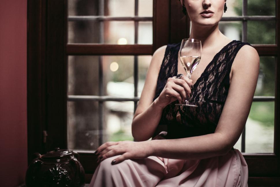 Free Image of Woman Sitting in Front of a Window Holding a Wine Glass 