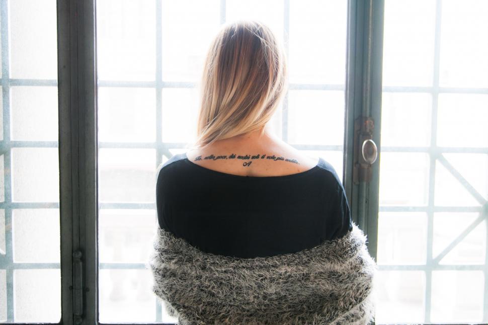 Free Image of Woman Standing in Front of Window Wearing Sweater 