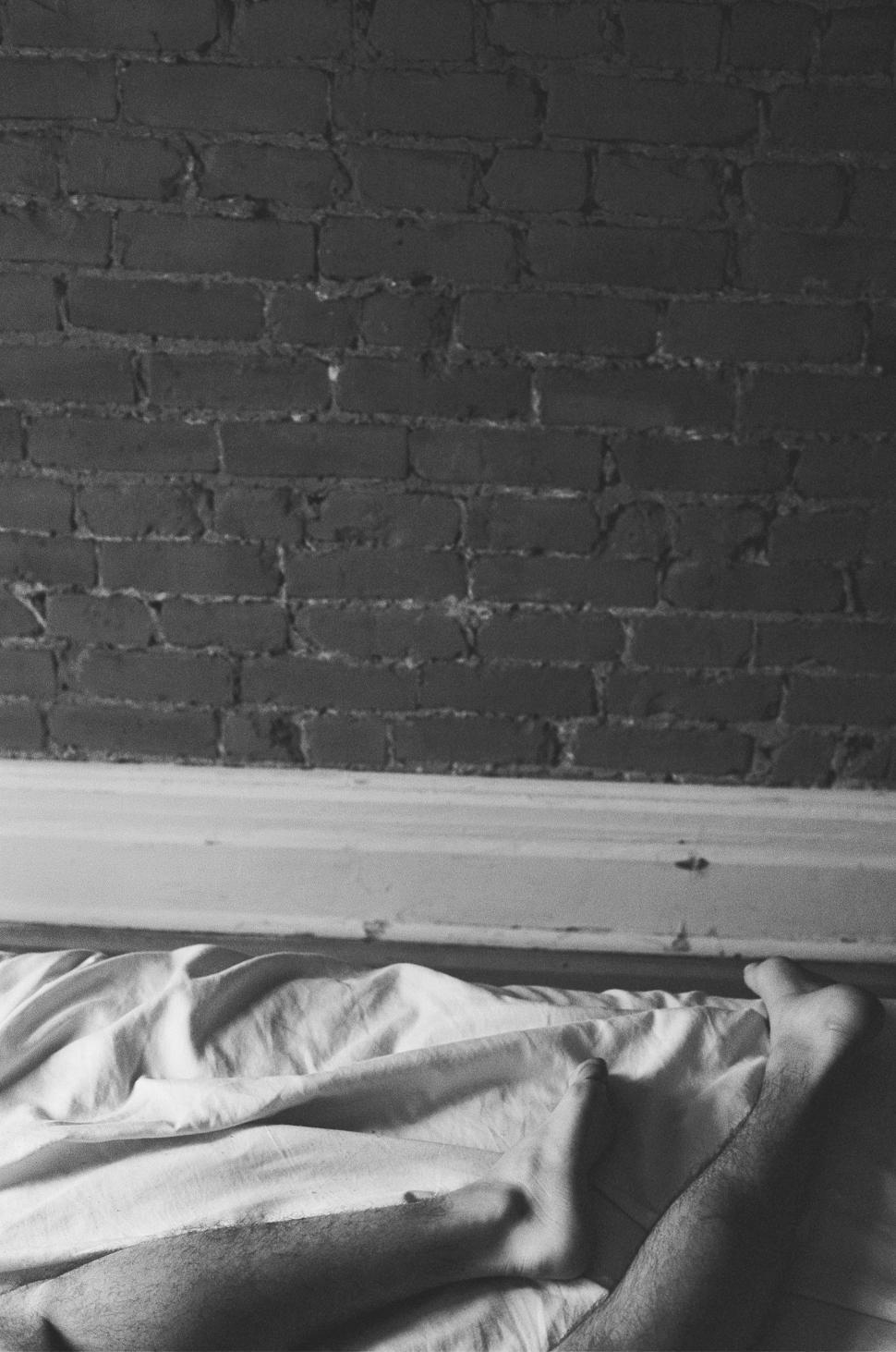 Free Image of Unmade Bed With Brick Wall Background 