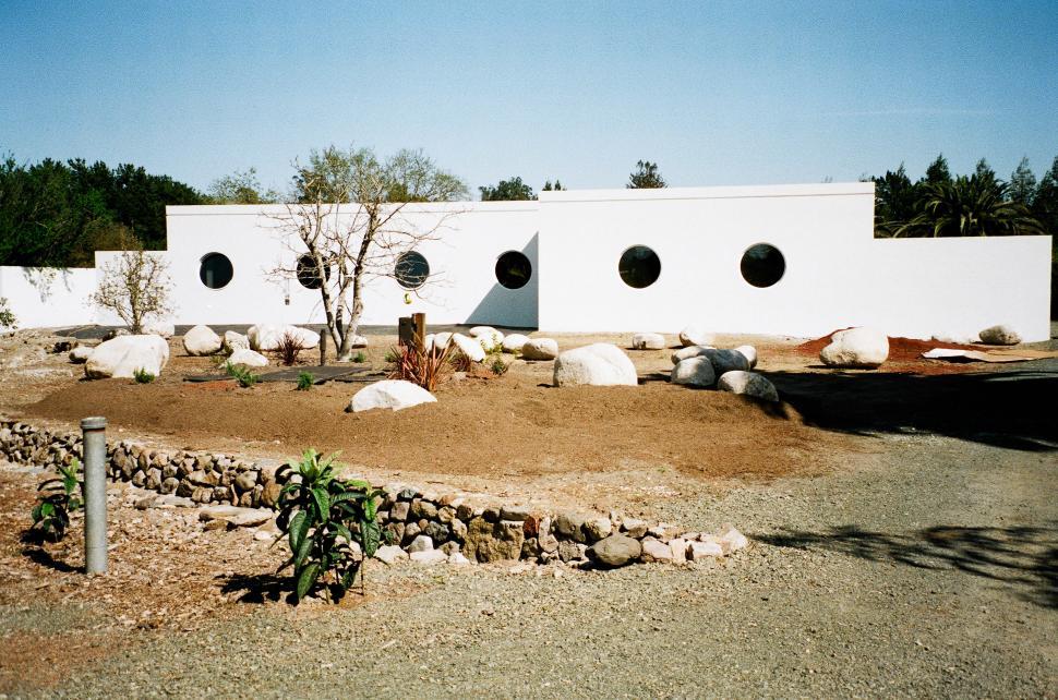 Free Image of White Building With Round Windows in Dirt Field 