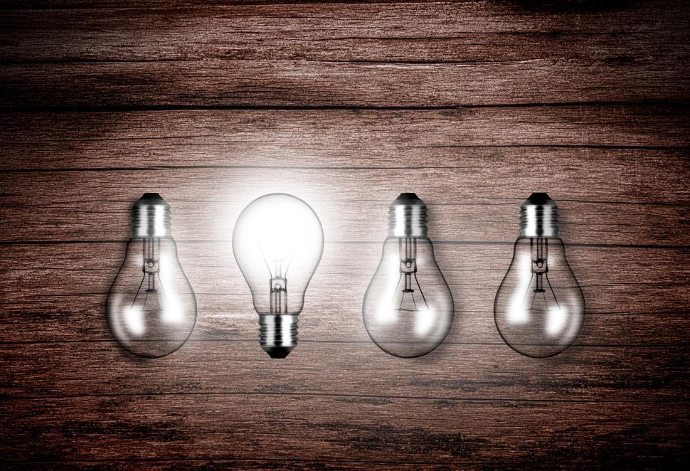 Free Image of Lightbulbs on wood - A glowing lightbulb contrasts with others a 