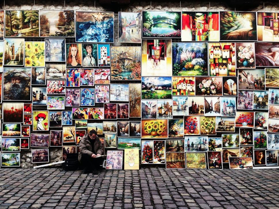 Free Image of Man Sitting in Front of Wall Covered With Pictures 