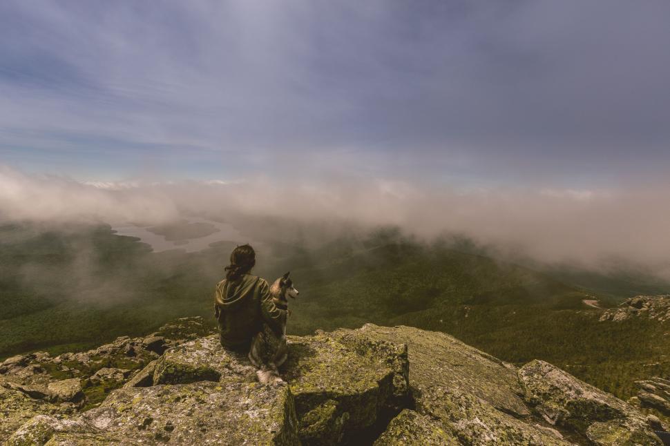 Free Image of Man Sitting on Top of a Mountain Holding a Gun 