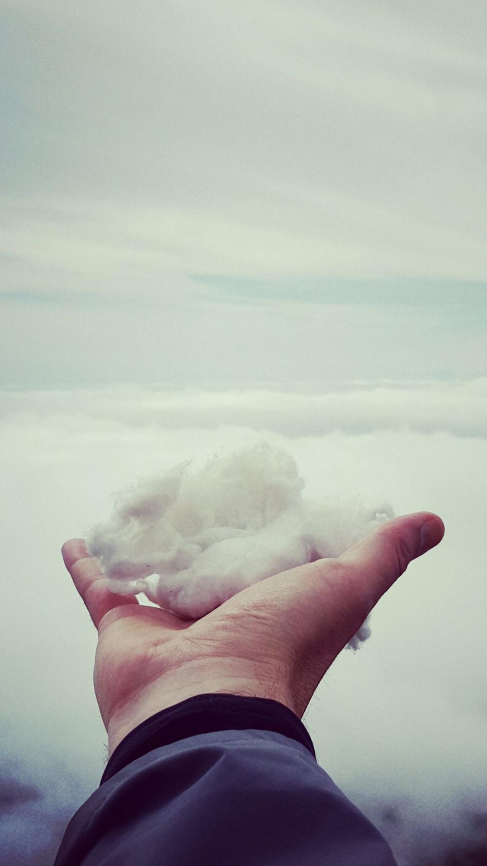 Free Image of Person Holding Out Hand Under Cloudy Sky 
