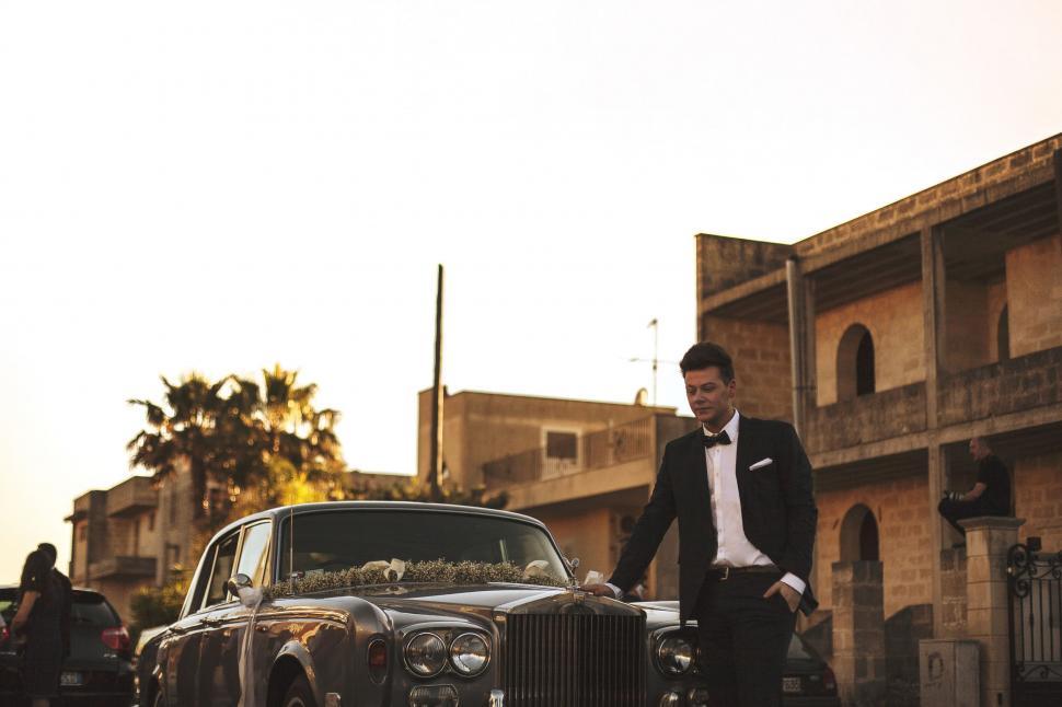 Free Image of Man in Tuxedo Standing Next to Car 