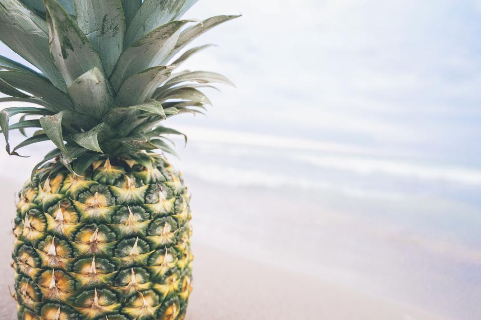 Free Image of Pineapple on Beach With Ocean Background 