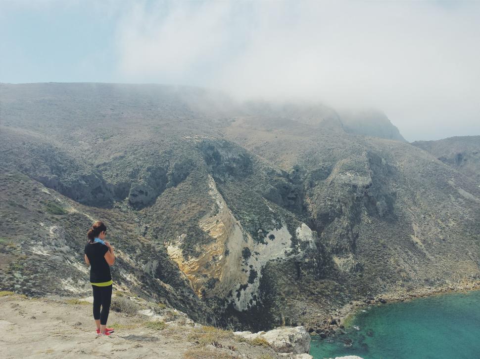 Free Image of Person Standing on Cliff Overlooking Body of Water 