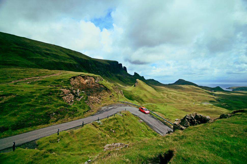 Free Image of Red Car Driving Down a Winding Road 