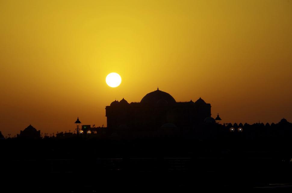 Free Image of The Sun Sets Over a Large Building 