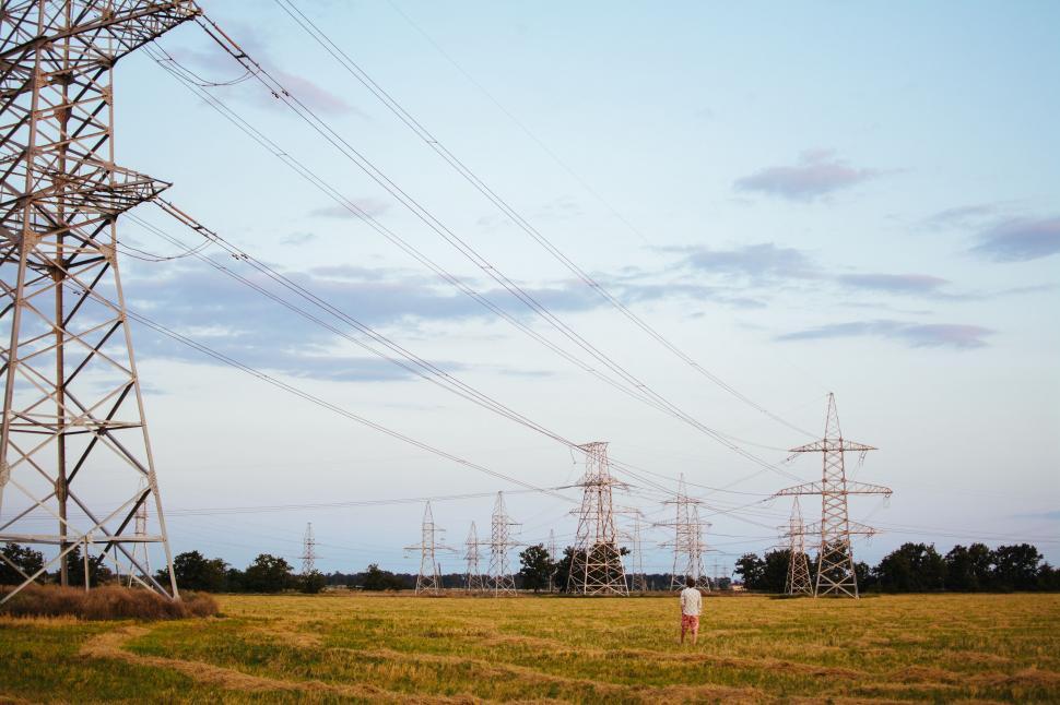 Free Image of Man Standing in Field Under Power Lines 