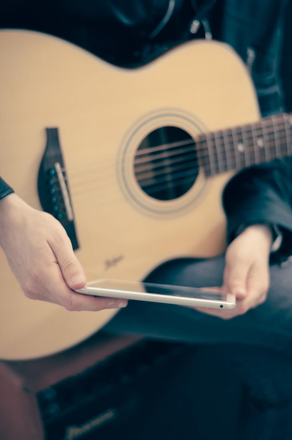 Free Image of Person Holding Cell Phone and Guitar 