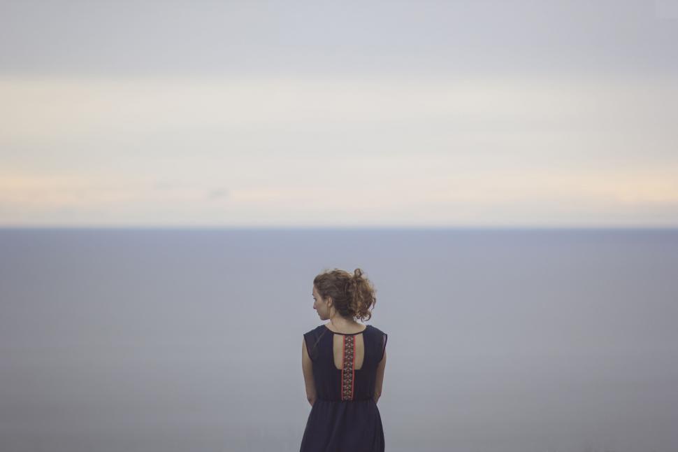 Free Image of Woman in Black Dress Standing on Beach 