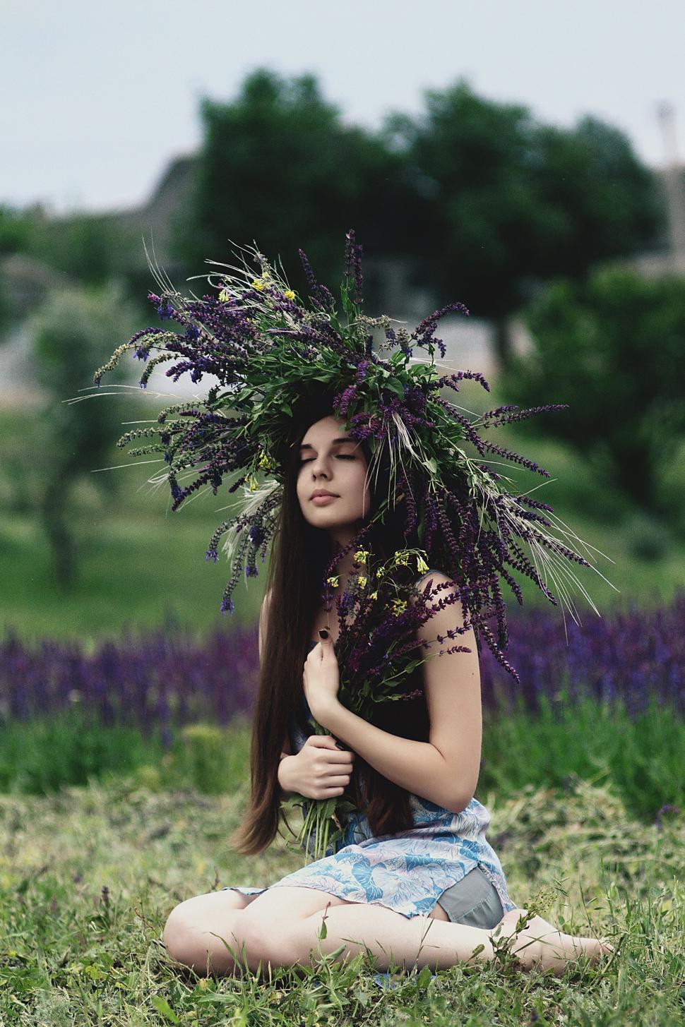 Free Image of Woman Sitting in Field With Flowers on Head 
