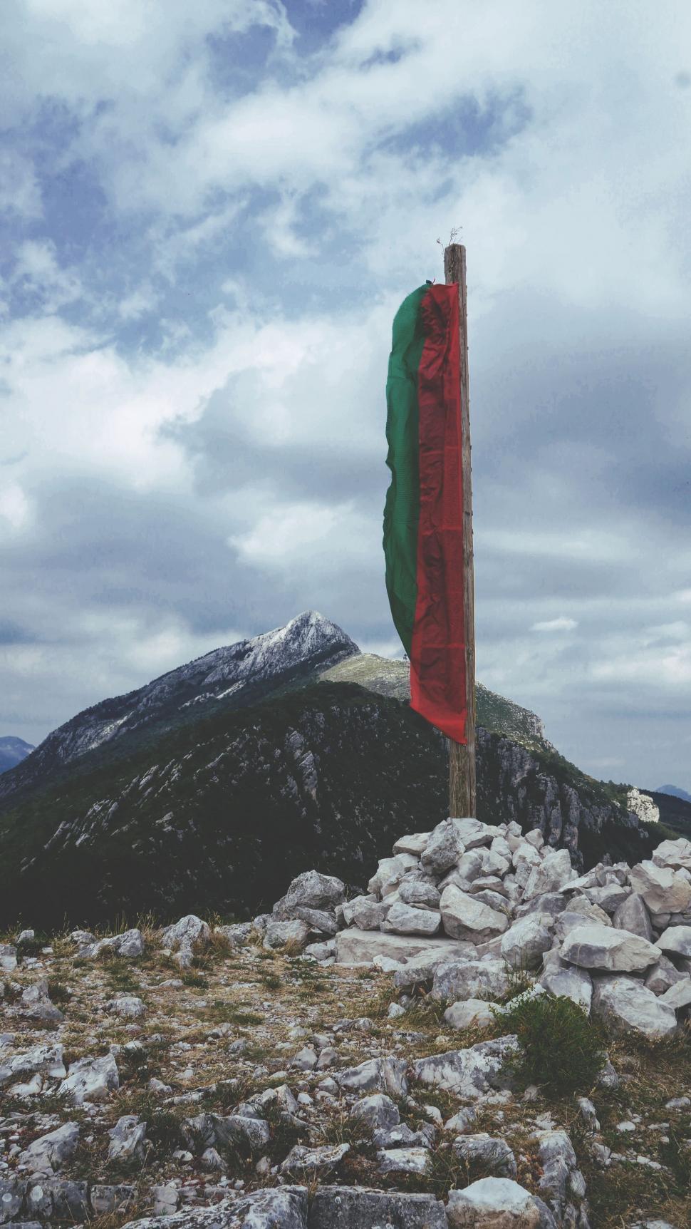 Free Image of Flag Flying Atop Mountain on Cloudy Day 