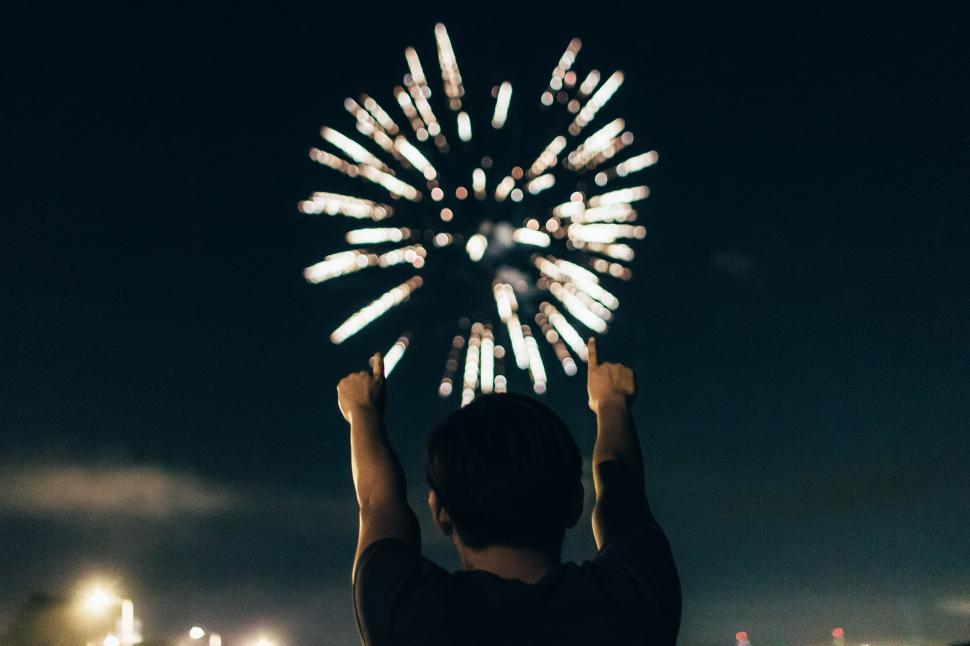 Free Image of Person Holding Hands Up in Front of Fireworks Display 