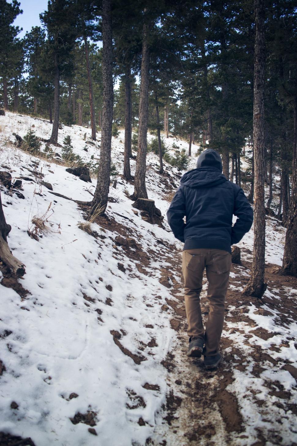 Free Image of Man Walking Up Snow Covered Hill 