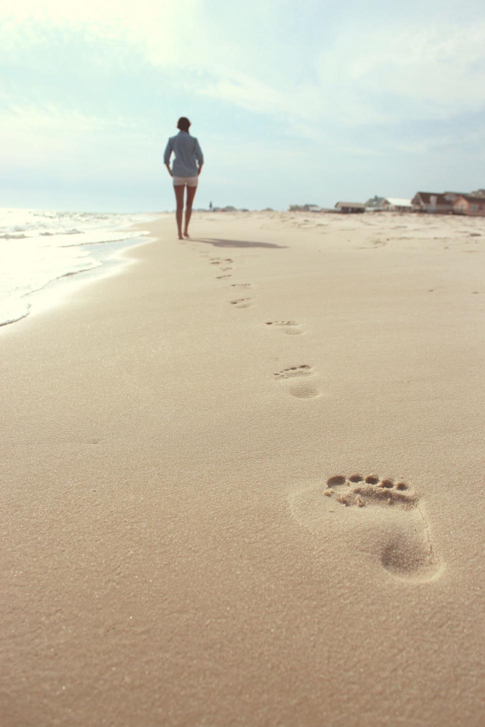 Free Image of Person Walking on Beach With Footprints in Sand 