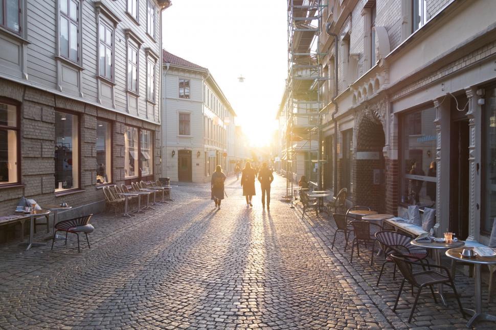 Free Image of Two People Walking Down a Cobblestone Street 
