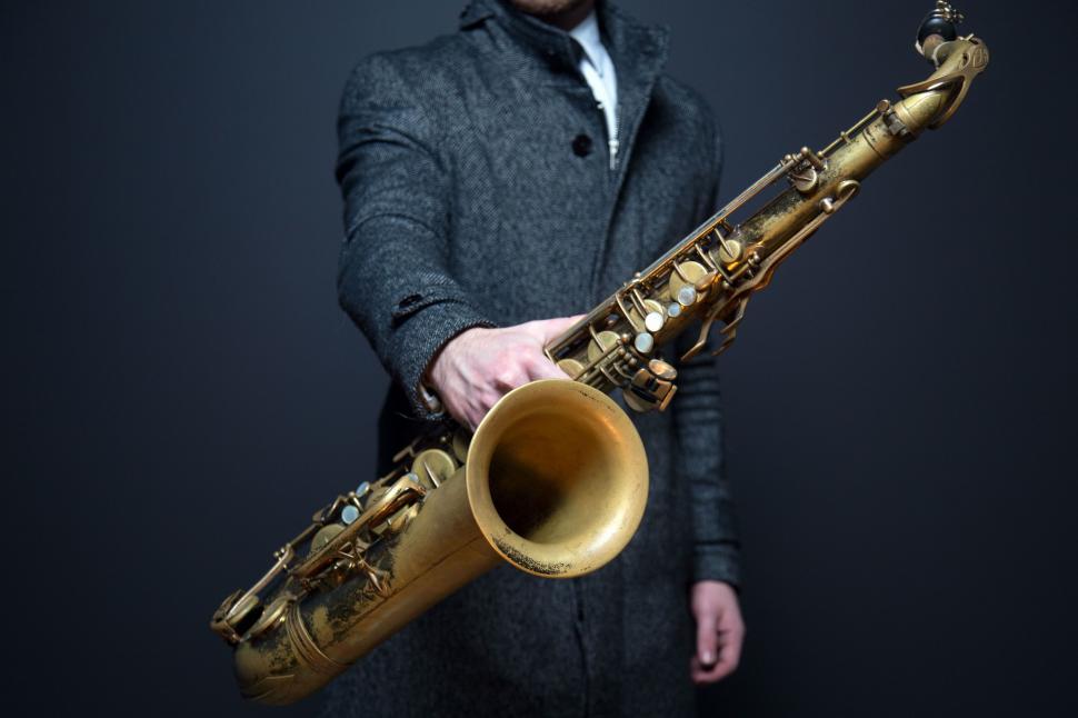 Free Image of Man Holding Saxophone in Right Hand 