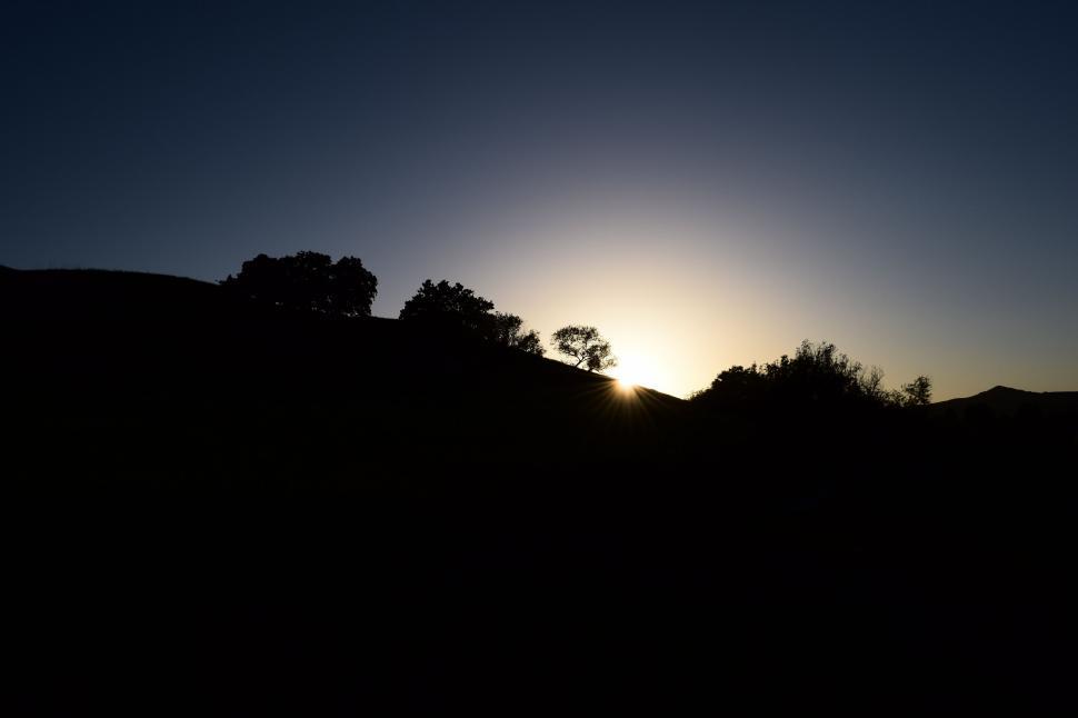 Free Image of Sun Setting Over Hill With Trees 