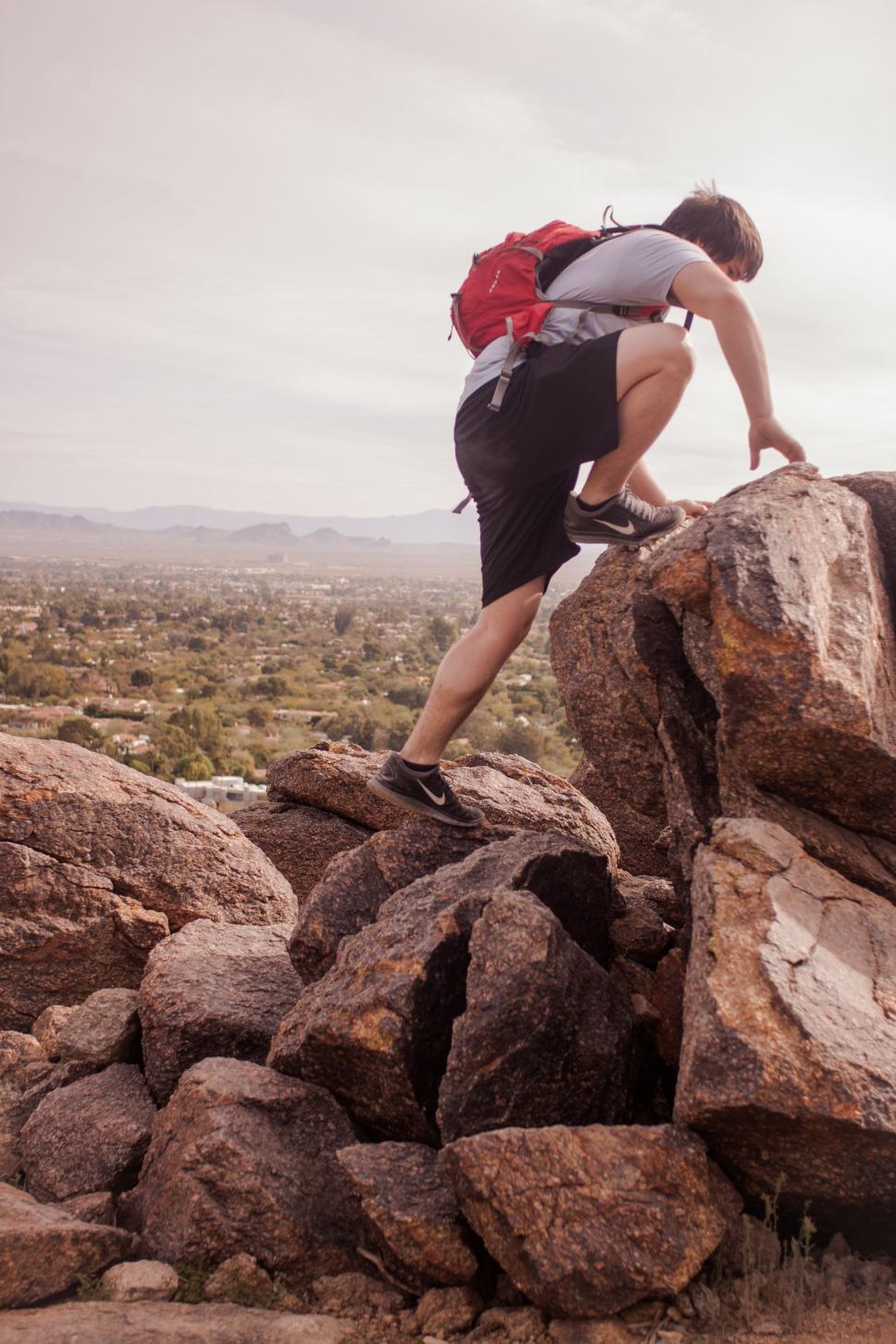 Free Image of Man Climbing Up the Side of a Large Rock 