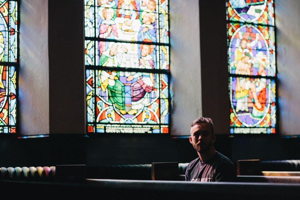 Free Image of Man Sitting in Front of Three Stained Glass Windows 