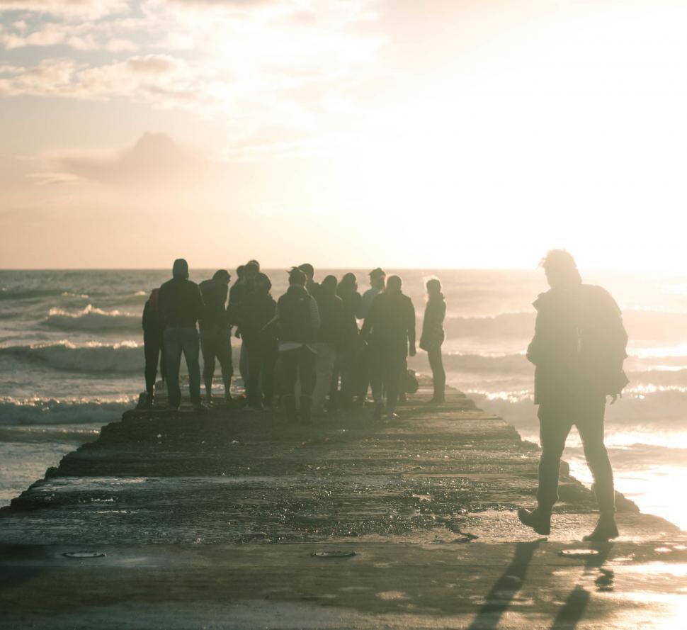 Free Image of Group of People Standing on Beach Next to Ocean 