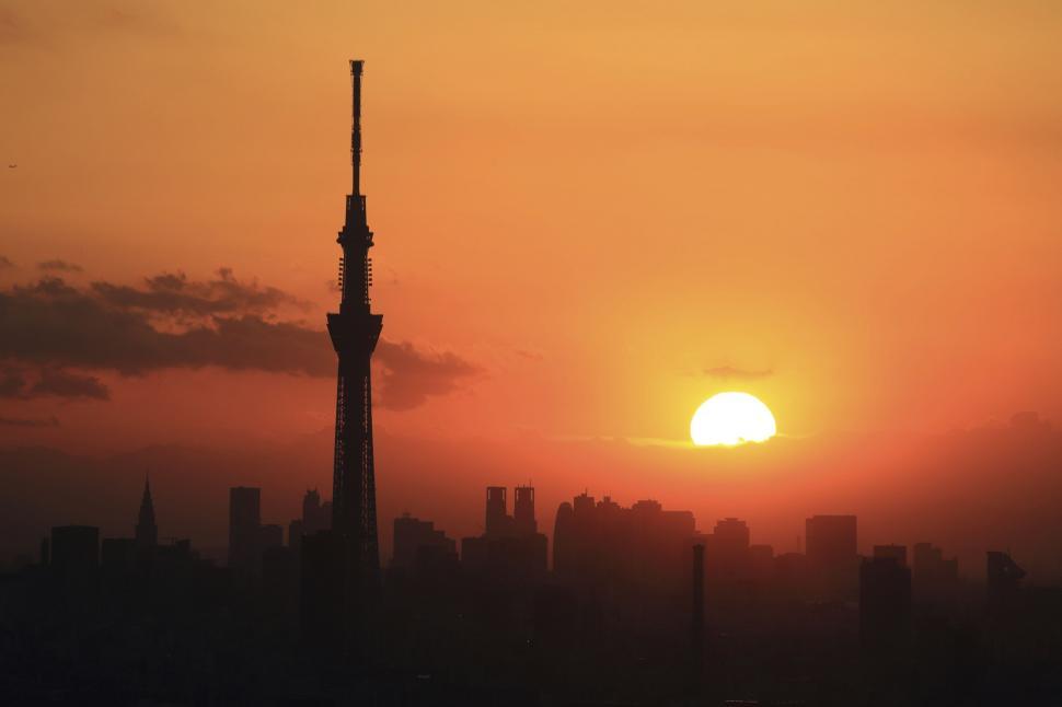 Free Image of Sun Setting Behind a Tall Building 
