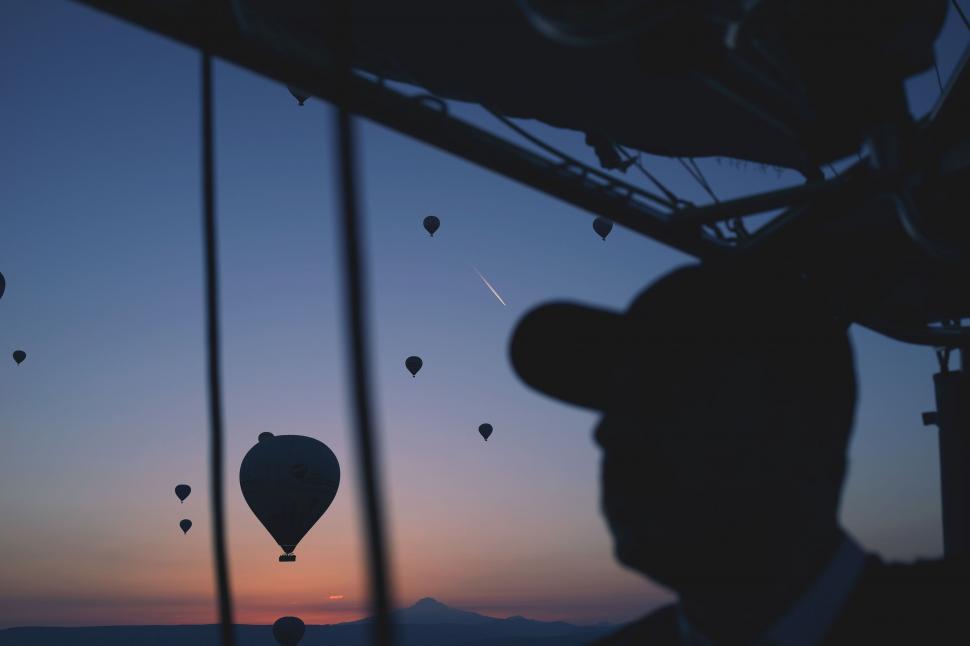 Free Image of Person Looking Out a Window at Hot Air Balloons 