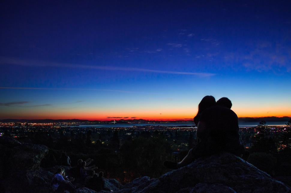 Free Image of Two People Sitting on a Rock at Sunset 