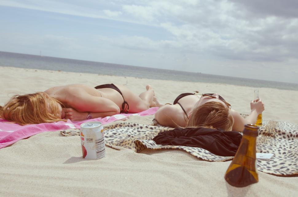 Free Image of Two Women Laying on Sandy Beach 