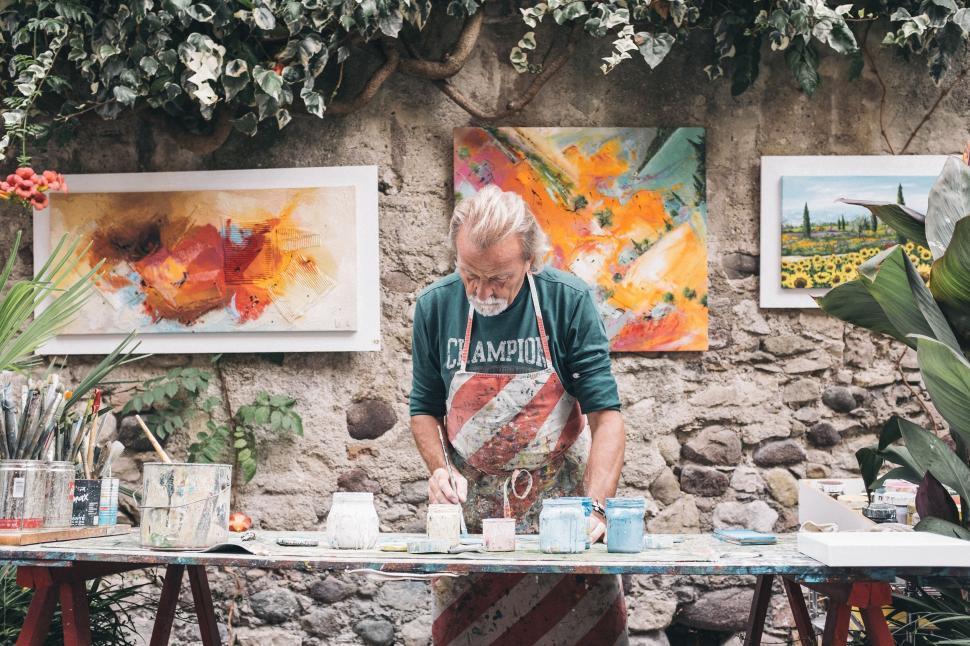 Free Image of Man Standing in Front of Table Covered in Paintings 