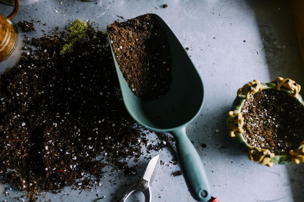 Free Image of Scoop of Dirt Next to Potted Plant 